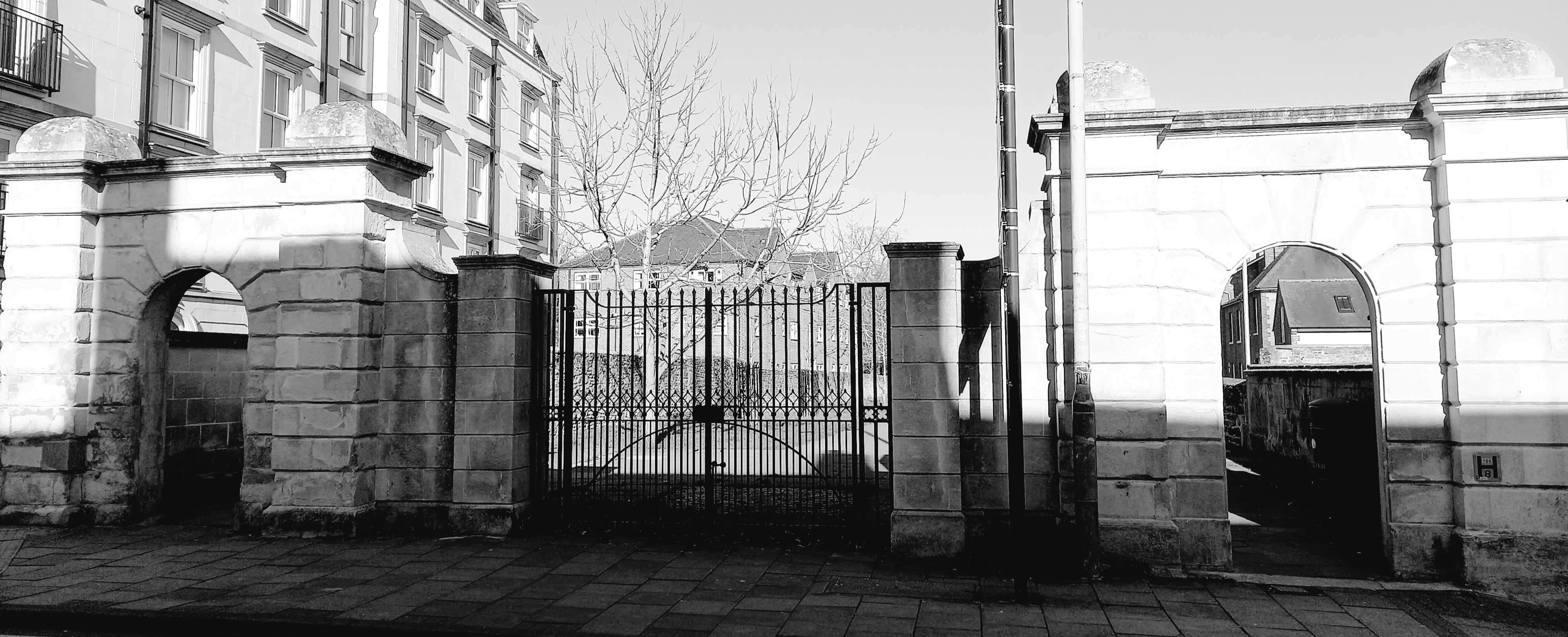 Big iron gates in the middle with two stone bowtopped doorways to either side.
